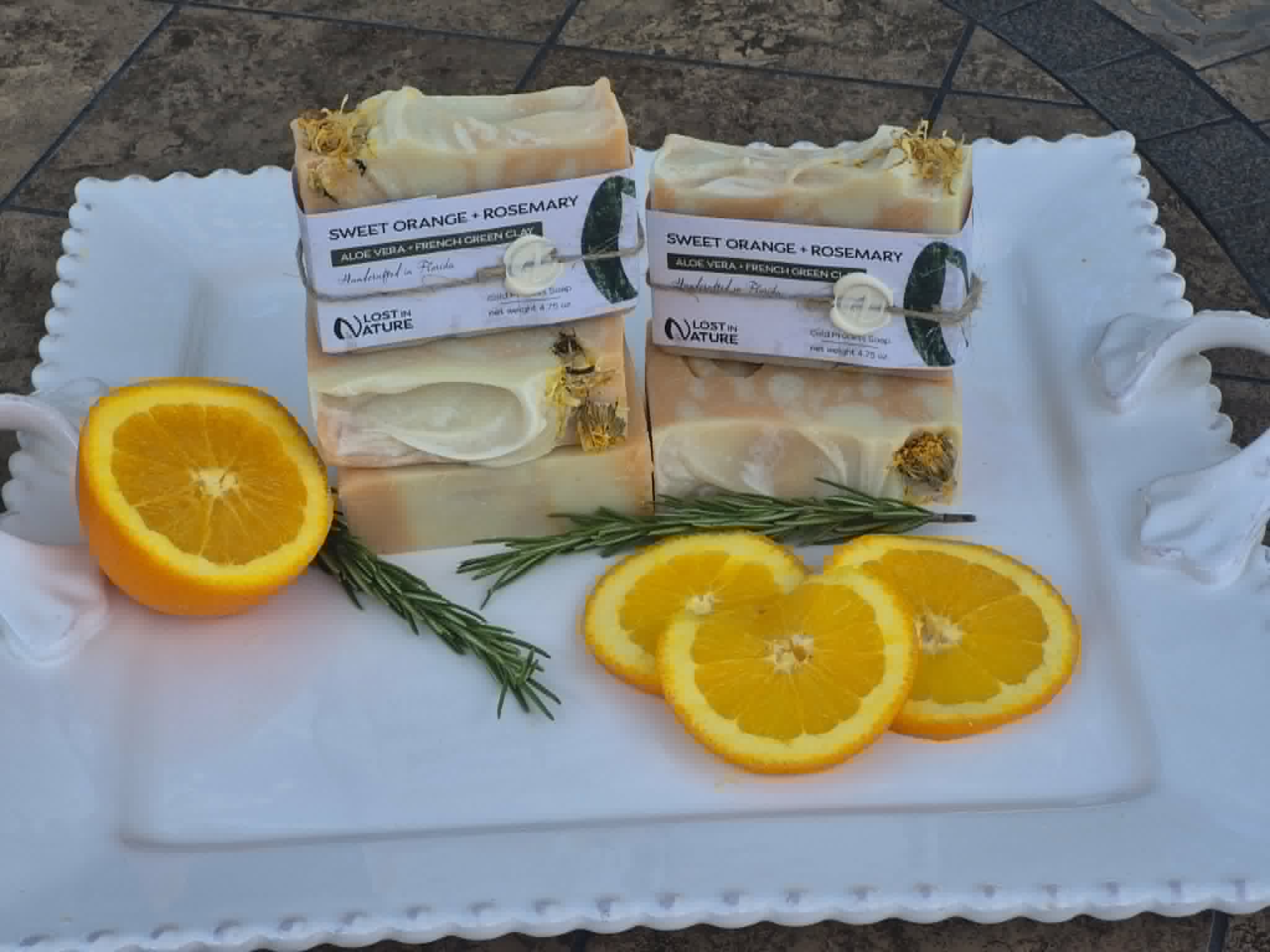 Sweet Orange and Rosemary soap arranged with fresh orange and rosemary